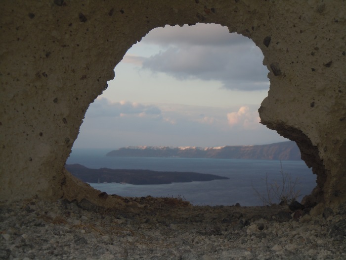 Caldera view framed by a rock opening on Santorini